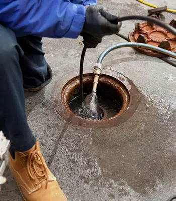 person putting black pipe on the ground with water