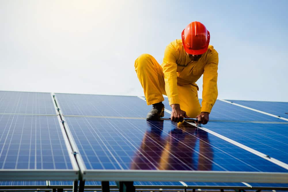 A man working on solar panels on the roof of the house